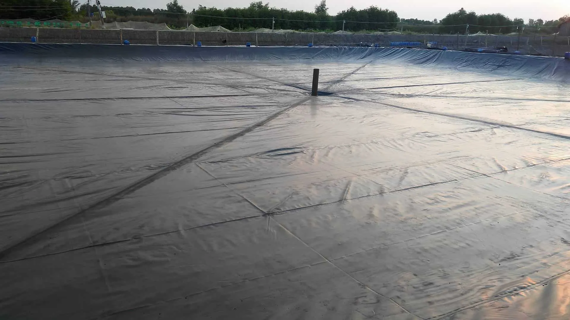 Bạt lót hồ tôm HDPE đang được chuẩn bị để thi công, thể hiện vật liệu địa kỹ thuật môi trường quan trọng trong nuôi trồng thủy sản.