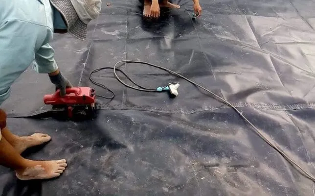 Công nhân đang thi công trải bạt và hàn nối bạt chống thấm HDPE trên diện tích lớn bằng phương pháp kéo trải