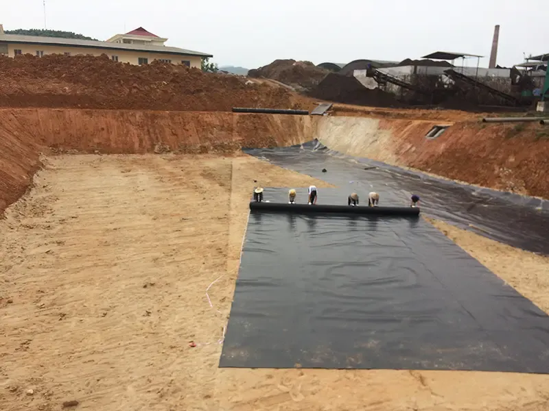 Công nhân kiểm tra bề mặt nền đất trước khi thi công màng HDPE để đảm bảo độ phẳng và chắc chắn