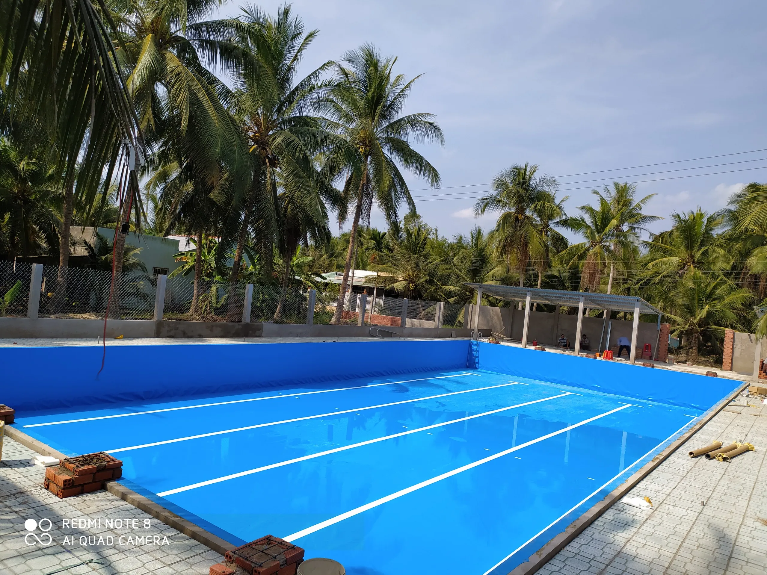 Hồ bơi lót bạt PVC màu xanh dương sáng, bền đẹp với nền xi măng.
