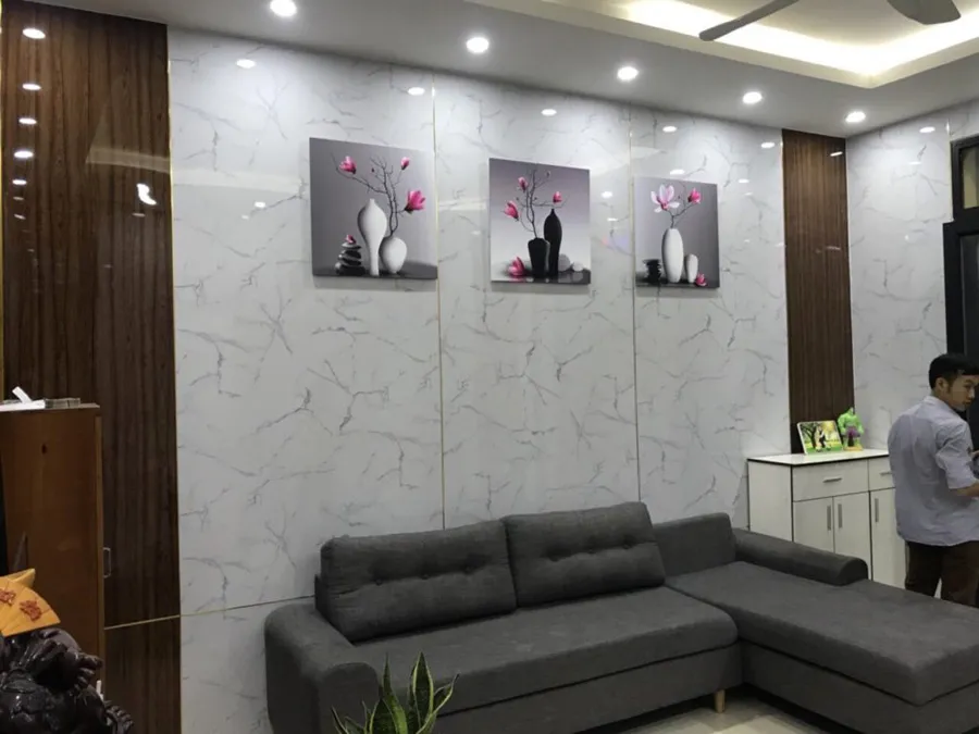 Không gian phòng khách được ốp alu vân đá, mang lại vẻ sang trọng với chi phí hợp lý