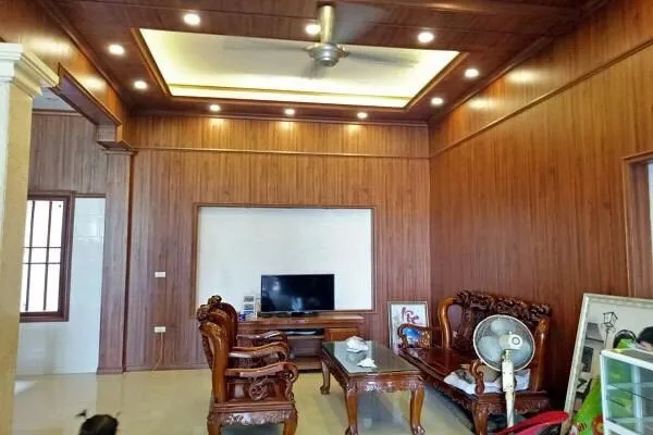 Không gian phòng khách rộng rãi ốp nhựa giả gỗ màu nâu trầm