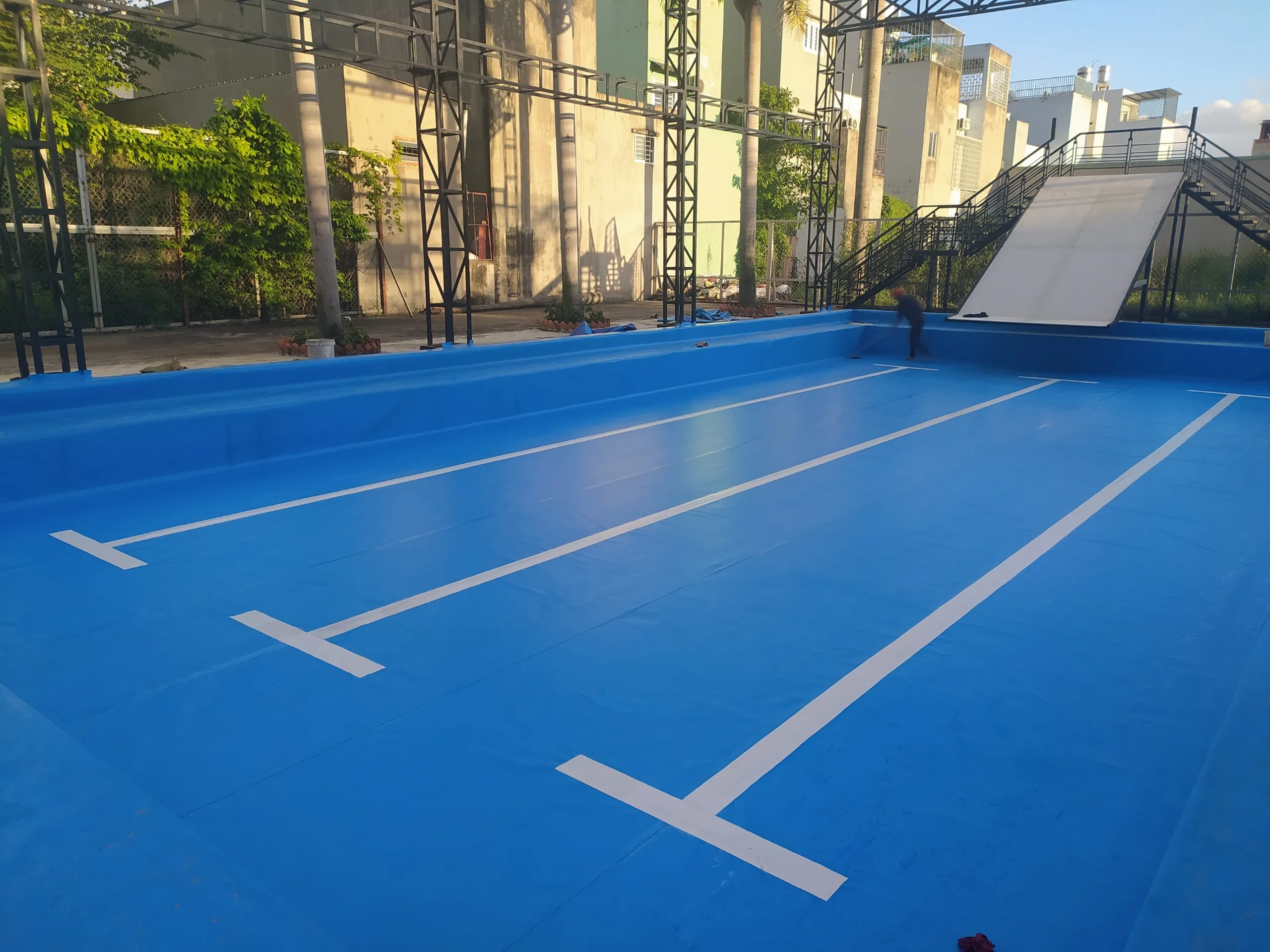 Kỹ thuật viên đang hoàn thiện công đoạn dán bạt PVC cho bể bơi lót bạt.