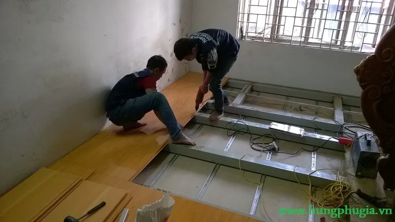 Kỹ thuật viên đang thi công lắp đặt tấm lót sàn PVC chịu lực, quy trình nhanh chóng
