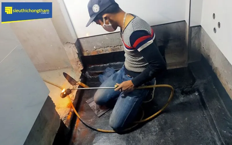 Kỹ thuật viên đang thi công màng chống thấm khò nóng chuyên dụng để xử lý sàn nhà vệ sinh bị thấm dột