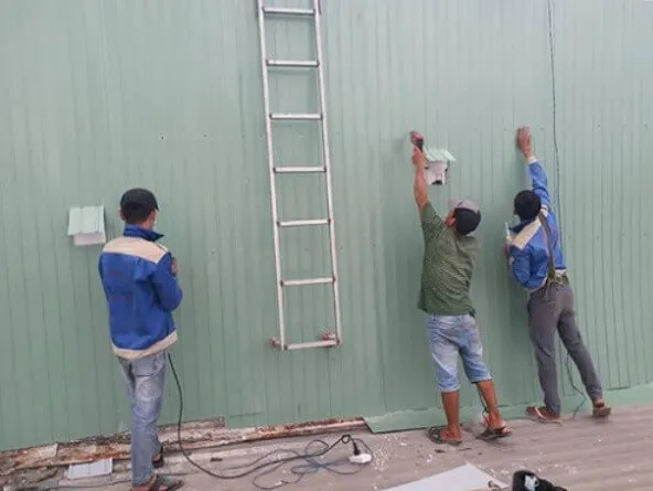 Kỹ thuật viên đang thực hiện thi công ốp tôn chống thấm chuyên nghiệp
