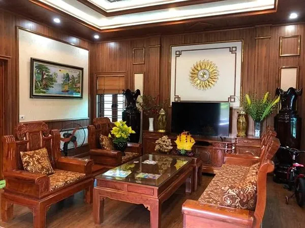 Người đàn ông ngồi trên ghế sofa trong phòng khách hiện đại ốp nhựa vân gỗ