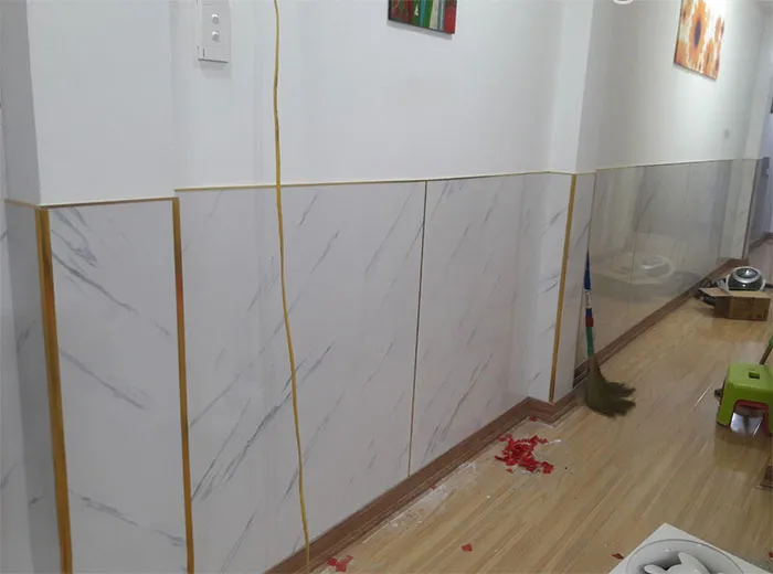 Ốp nhựa chân tường phòng khách sử dụng tấm PVC giả đá màu xám, mang vẻ đẹp sang trọng.