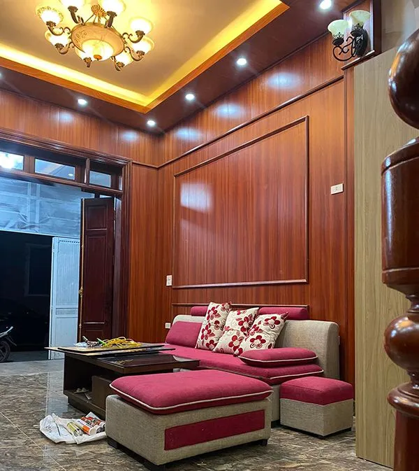 Phòng khách sang trọng với tường và trần ốp nhựa vân gỗ kết hợp ánh sáng