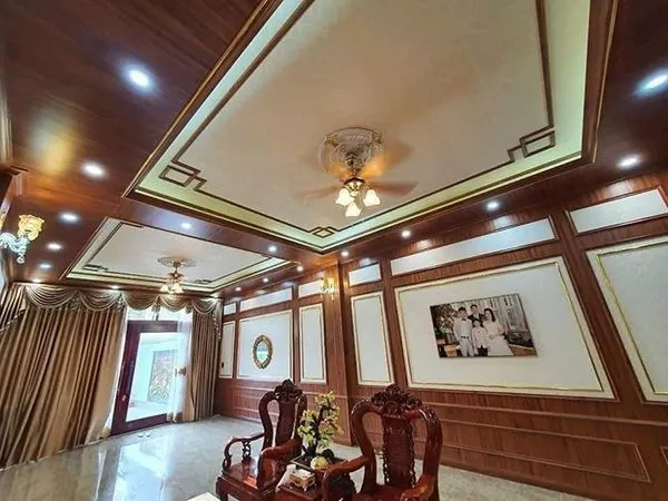 Phòng khách với bộ sofa và tường ốp nhựa vân gỗ tông màu ấm