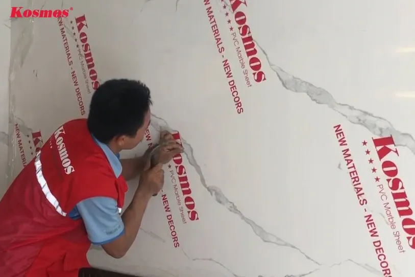 Sử dụng súng bắn đinh để cố định tấm nhựa PVC giả vân đá tại các vị trí ít nhìn thấy, giúp tăng cường độ chắc chắn cho toàn bộ mảng tường ốp.