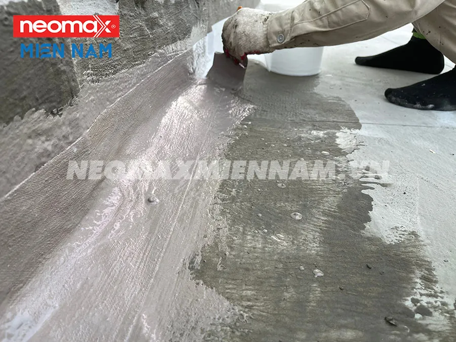 Thợ chống thấm đang dán lưới polyester vào chân tường