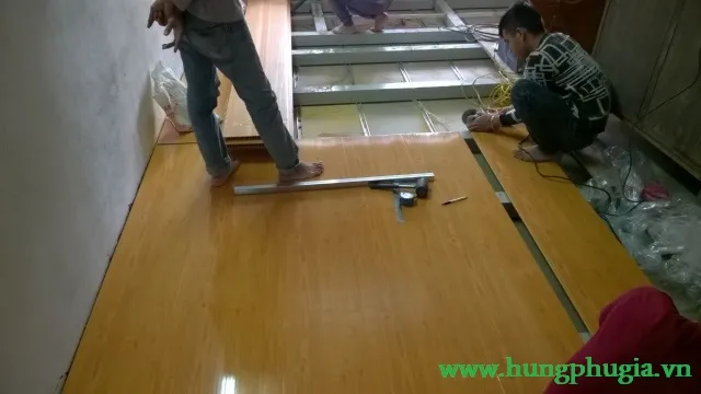 Thợ đang lắp đặt tấm lót sàn PVC cho gác lửng, tạo không gian sống tiện nghi