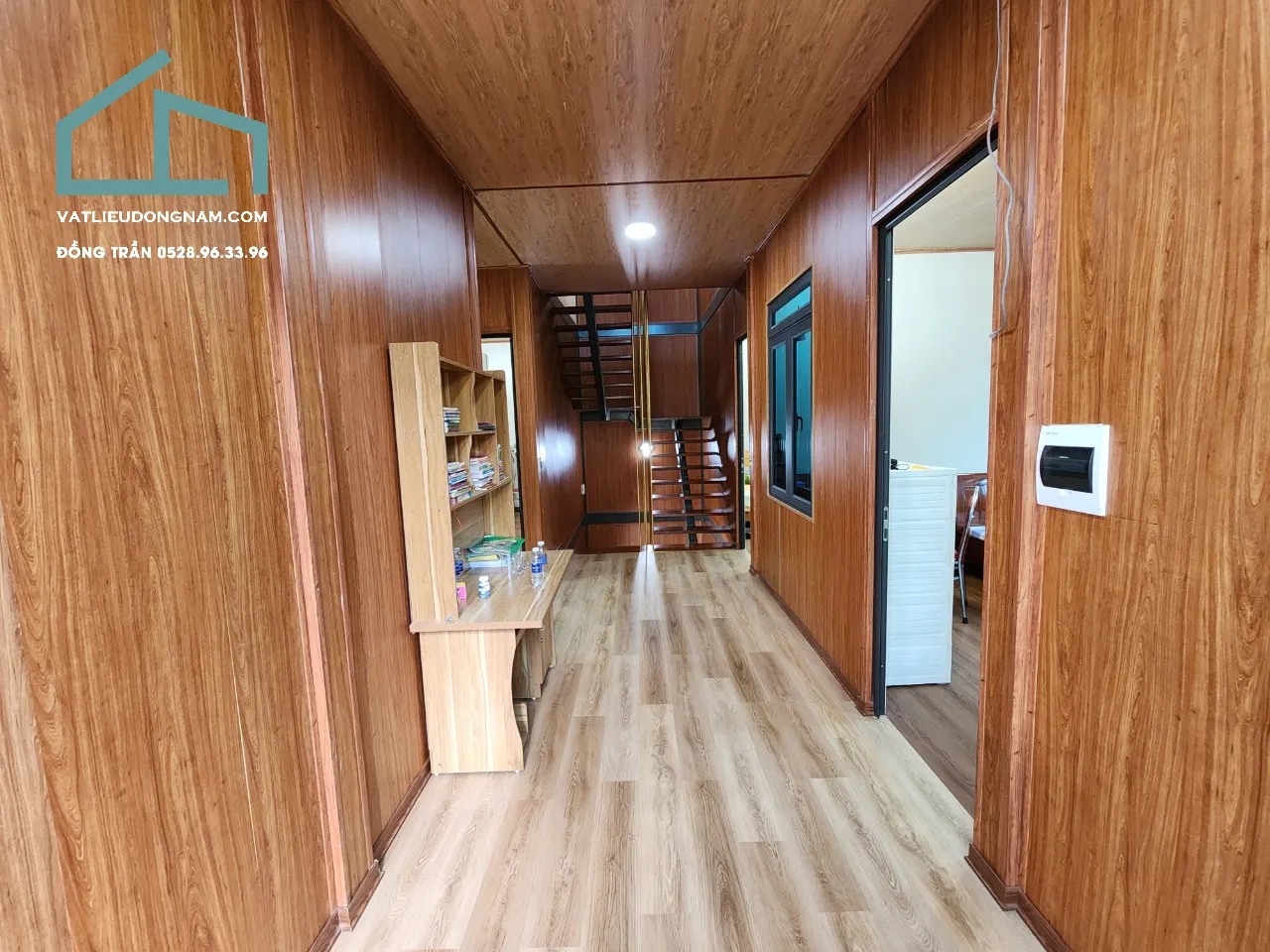 Tường phòng khách được ốp bằng tấm nhựa vân gỗ mang lại vẻ ấm cúng